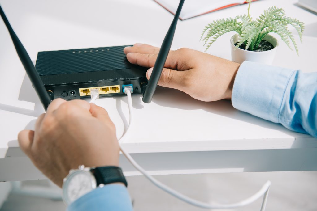 partial view of IT Technician plugging router on office desk depicting Office Network Setup Services