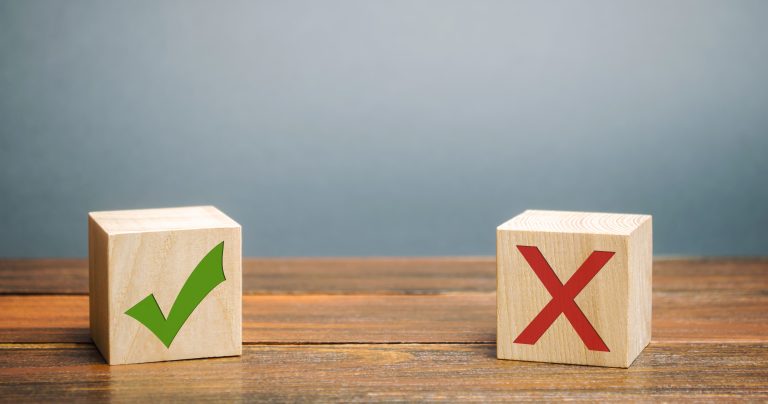 Two wood blocks sitting on a wood table, wood blocks have a checkmark on one and an X on the other, depicting the honest truth about MSPs