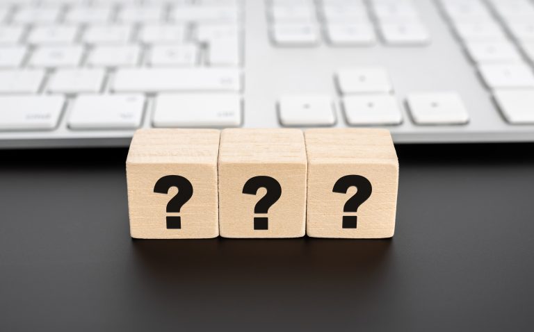 Questions Mark on wooden block and computer keyboard. FAQ Answer, depicting Questions to Ask an MSP